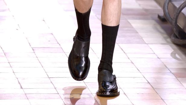 Ein Mann trägt schwarze Socken und Lederschuhe mit Schnallen.
