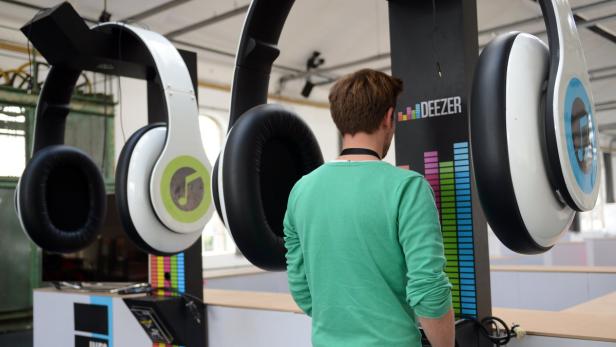 Ein Mann betrachtet überdimensionale Kopfhörer und ein Deezer-Display.