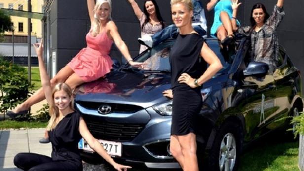 Mehrere Frauen posieren auf und um einen blauen Hyundai Tucson.
