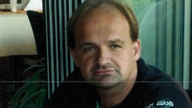 Porträt eines Mannes mit dunklem T-Shirt vor einem Fenster.