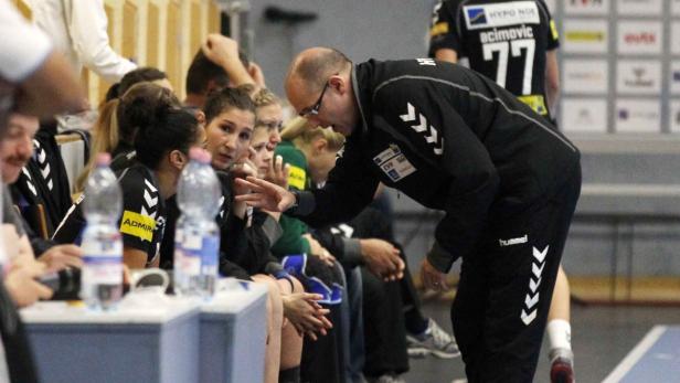 Ein Trainer bespricht sich mit seiner Handballmannschaft auf der Bank.