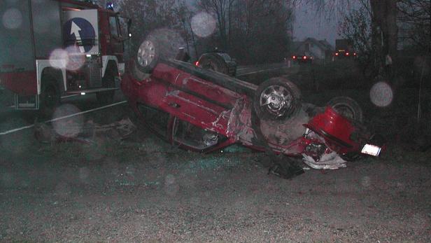 Ein rotes Auto liegt nach einem Unfall auf dem Dach, ein Feuerwehrwagen steht daneben.