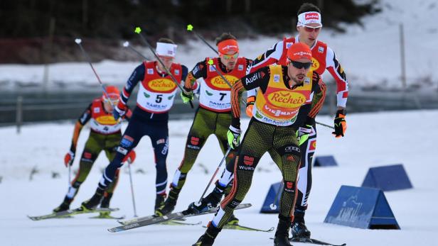 Mehrere Skilangläufer nehmen an einem Wettkampf im Schnee teil.