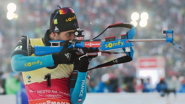 Ein Biathlet zielt mit seinem Gewehr auf eine Zielscheibe.