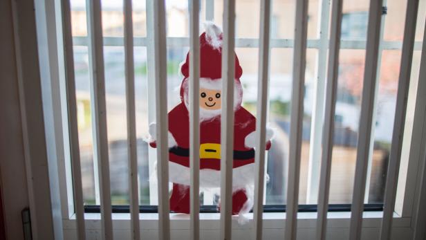 Ein Weihnachtsmann aus Papier hinter Gefängnis-Gittern