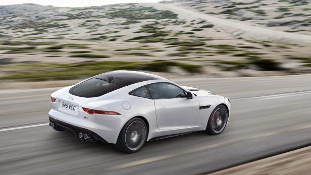 Ein weißer Jaguar F-Type fährt auf einer Landstraße.