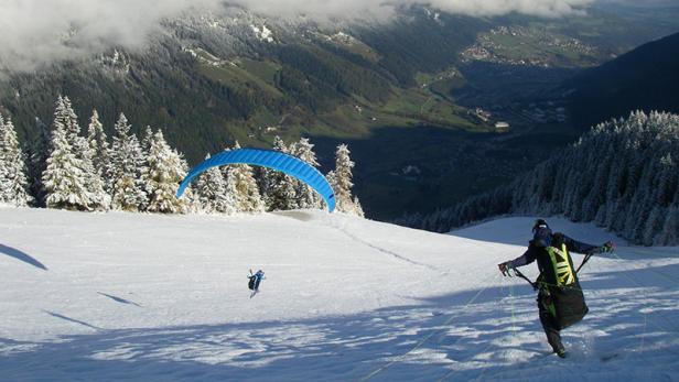 Ein Gleitschirmflieger bereitet sich auf einem schneebedeckten Hang auf den Start vor.