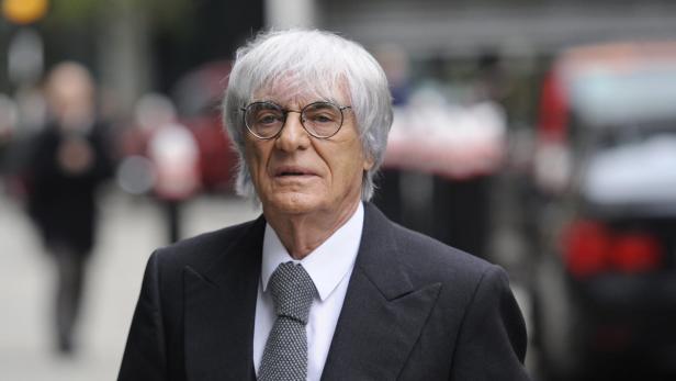 Bernie Ecclestone mit Anzug und Brille auf einer Straße.