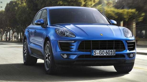 Ein blauer Porsche Macan fährt auf einer Straße in einer Stadt.