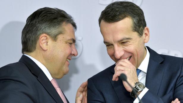 Zwei Männer in Anzügen unterhalten sich lächelnd.