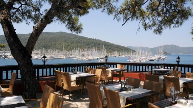 Ein Restaurant mit Blick auf einen Yachthafen mit vielen Segelbooten.