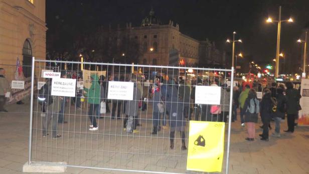 Eine Demonstration gegen Zäune vor einem Gebäude in der Nacht.