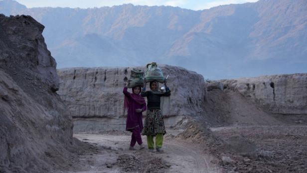 Afghanische Mädchen tragen einen Sack mit Kohle in ihre Häuser in der Nähe von Jalalabad.