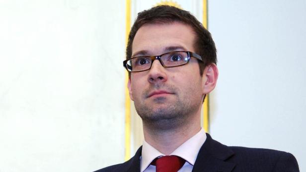 Ein Mann mit Brille, Anzug und roter Krawatte blickt nach oben.