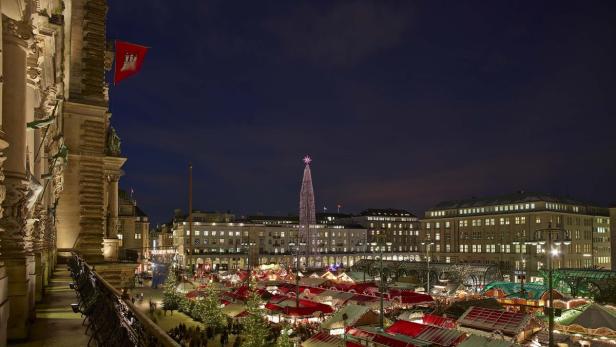 Blick auf den Hamburger Weihnachtsmarkt bei Nacht mit beleuchtetem Weihnachtsbaum.