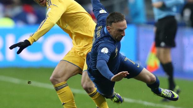 Ein Fußballspieler im blauen Trikot stürzt während eines Spiels.