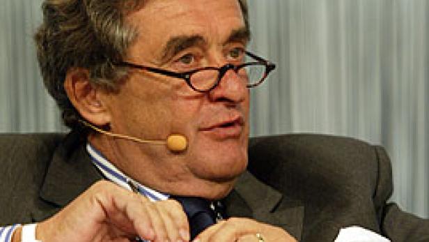 Ein älterer Mann mit Brille und Anzug spricht bei einer Konferenz.