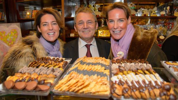 Drei Personen stehen vor einer Auslage mit verschiedenen Weihnachtsplätzchen.