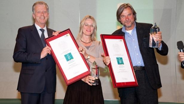 Drei Personen präsentieren Urkunden und Glaspokale.