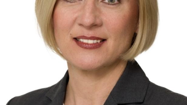 Porträt einer Frau mit blonden Haaren und einem grauen Blazer.