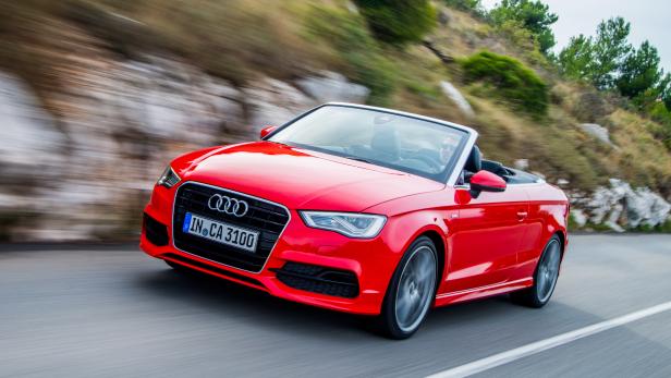 Ein rotes Audi Cabriolet fährt auf einer Küstenstraße.