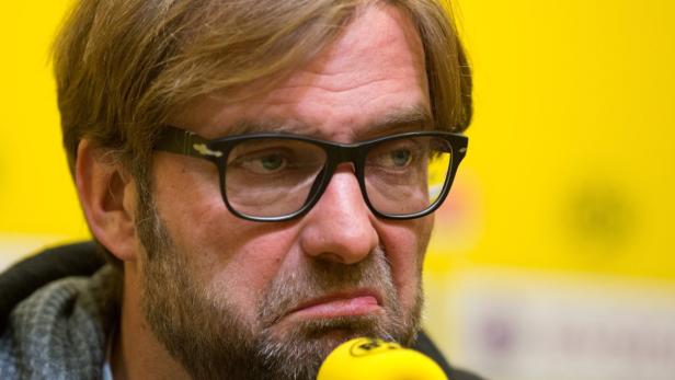 Jürgen Klopp bei einer Pressekonferenz vor einem gelben Hintergrund.