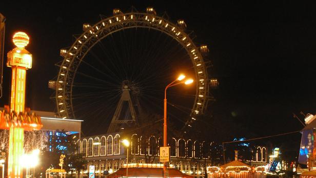 Das Wiener Riesenrad und andere Fahrgeschäfte sind nachts beleuchtet.