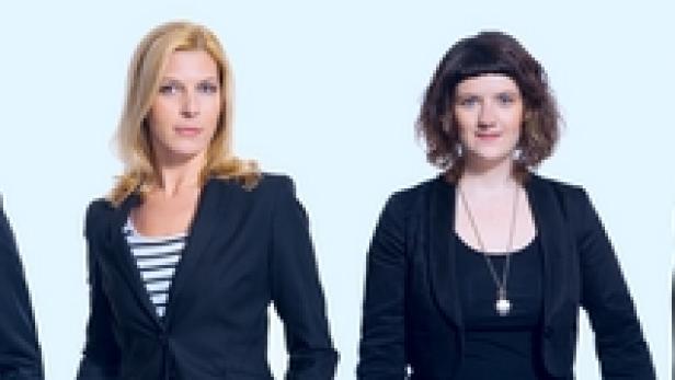 Vier Personen in formeller Kleidung stehen nebeneinander vor einem hellblauen Hintergrund.