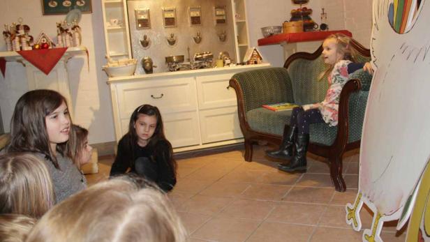 Eine Gruppe von Mädchen sitzt in einem Raum, während ein Mädchen auf einem Sofa sitzt.