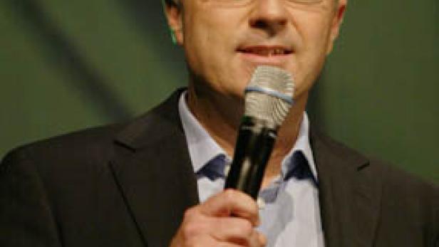 Ein Mann mit Brille spricht in ein Mikrofon.
