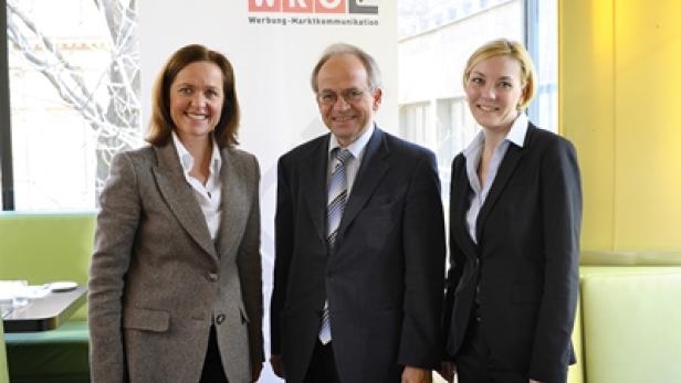 Drei Personen posieren vor einem WKO-Hintergrund für ein Foto.