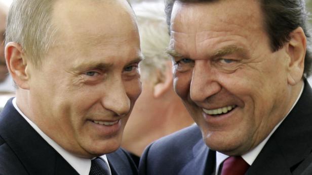 Wladimir Putin und Gerhard Schröder stehen lächelnd nebeneinander.