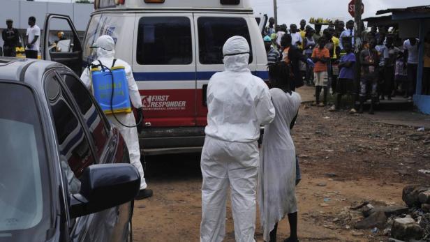 In Monrovia bringen Seuchenhelfer eine Frau in Quarantäne, die vermutlich an Ebola erkrankt ist. Die Helfer sind überfordert