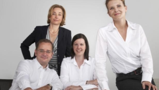 Ein Team aus vier Personen posiert für ein Gruppenfoto.