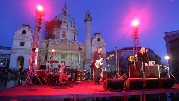 Eine Band spielt vor der Karlskirche in Wien auf einer Bühne.