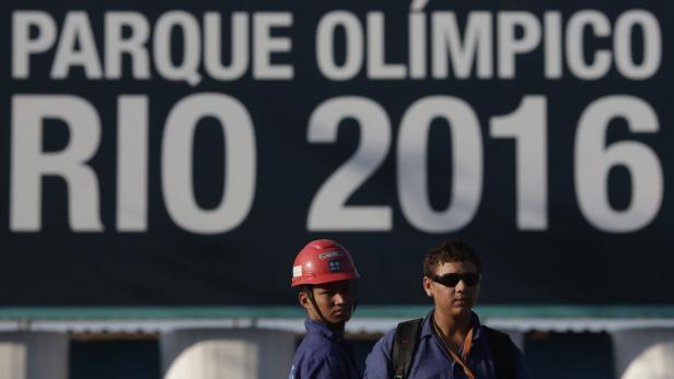 Zwei Arbeiter stehen vor einem Schild mit der Aufschrift „Parque Olímpico Rio 2016“.