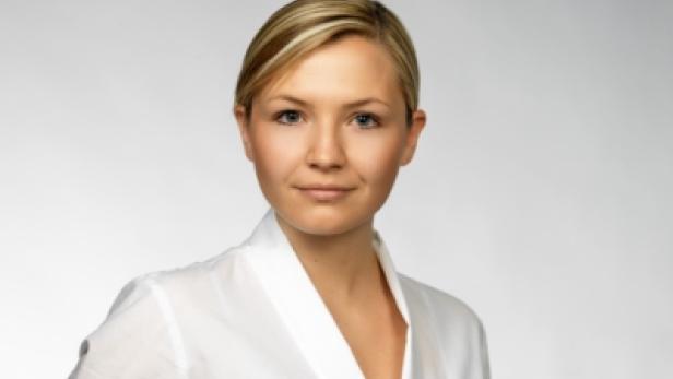 Porträt einer jungen Frau mit blonden Haaren und einem weißen Hemd.