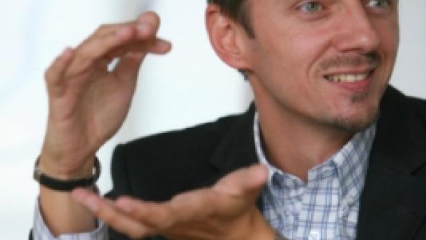 Ein Mann im Anzug gestikuliert mit seinen Händen.
