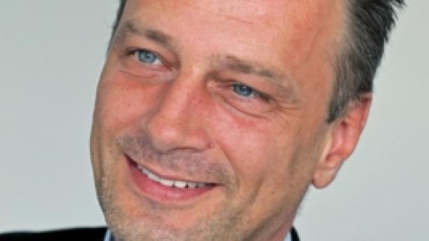 Ein lächelnder Mann im Anzug mit Krawatte.