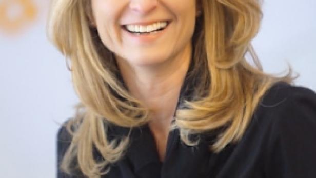 Eine lächelnde Frau mit blonden Haaren und einem schwarzen Oberteil.