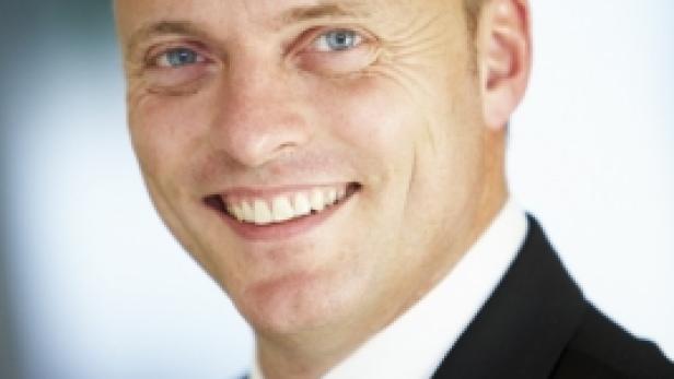 Ein lächelnder Mann im Anzug mit roter Krawatte.