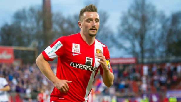 Ein Fußballspieler in einem roten Trikot mit der Aufschrift „Flyeralarm“ läuft auf dem Spielfeld.