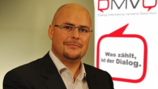 Ein Mann mit Brille und Anzug vor dem Logo des DMVÖ (Dialog Marketing Verband Österreich).