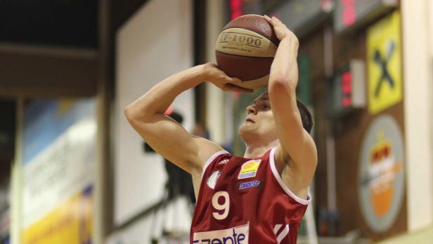 Ein Basketballspieler mit rotem Trikot und der Nummer 9 wirft einen Ball.