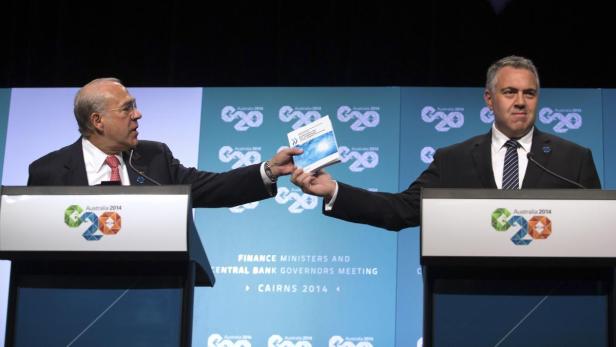 Zwei Männer übergeben sich ein Dokument während eines G20-Finanzministertreffens in Cairns, 2014.