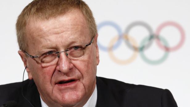 Ein Mann mit Brille spricht vor dem Hintergrund der olympischen Ringe.