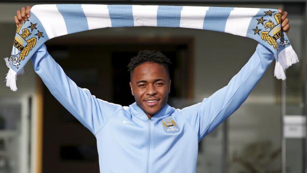 Raheem Sterling hält einen Schal von Manchester City hoch.