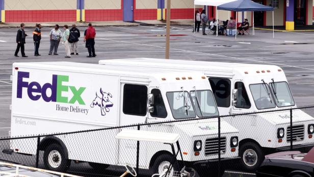 Zwei weiße FedEx Home Delivery-Fahrzeuge stehen auf einem Parkplatz.