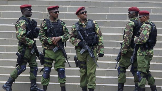 Fünf bewaffnete Soldaten in Tarnuniform stehen vor einer Treppe.