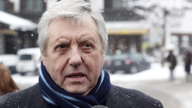 Ein älterer Mann mit Schal wird im Schnee interviewt.